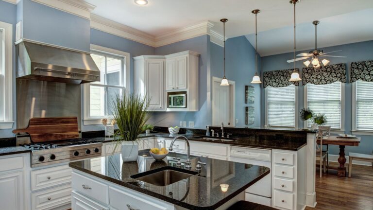 Kitchen with white cabinets, dark granite island and pendant lights