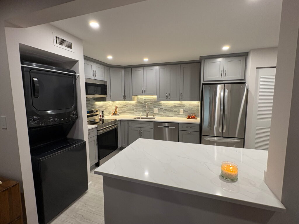Remodeled kitchen with gray cabinets, white quartz island and stainless steel appliances