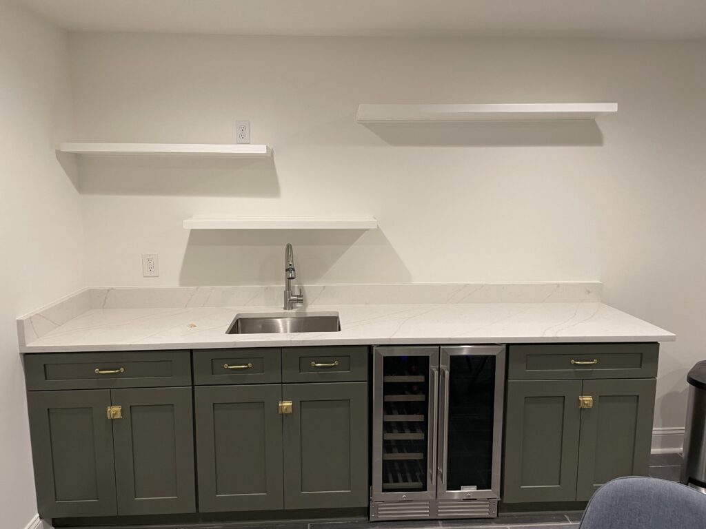 New kitchen with sage green lower cabinets, open shelving and a wine fridge