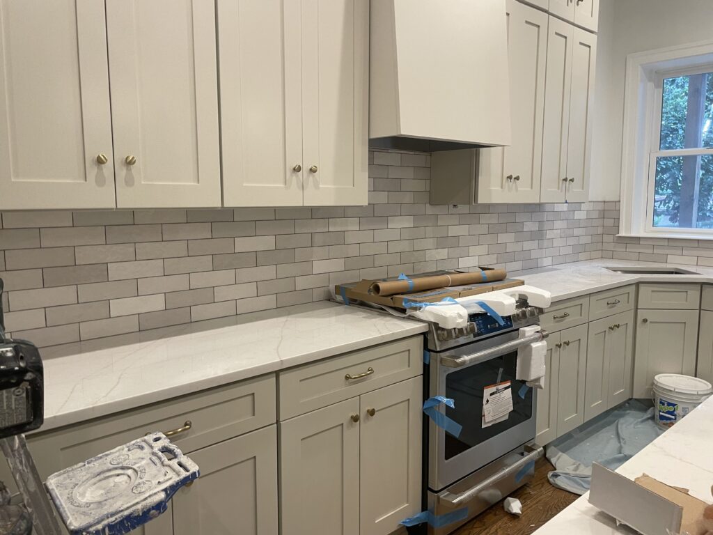 Subway tile backsplash being installed in a white kitchen