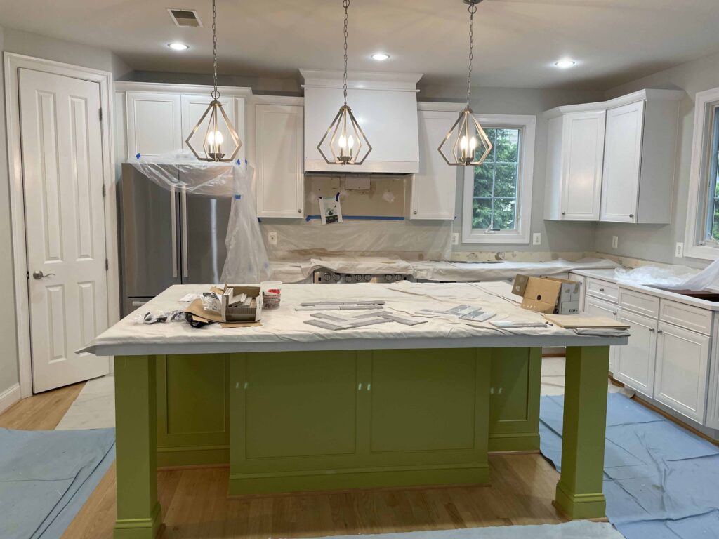 Kitchen remodel with white cabinets, green island and pendant lights