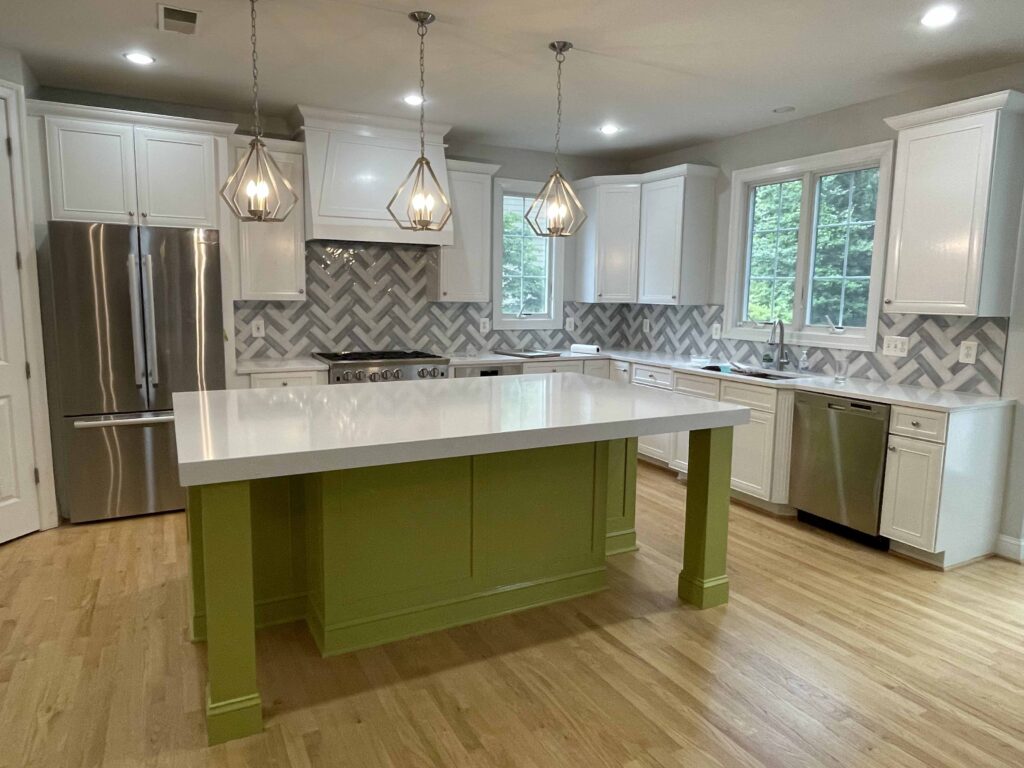 Finished kitchen with a green island, white countertops and pendant lights