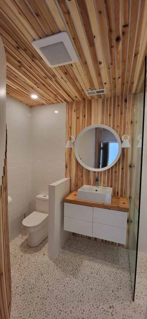 Bathroom with a wood slat accent wall, round mirror and vessel sink