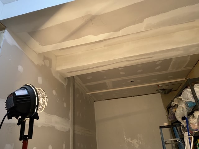 Basement drywall work in progress with a work light